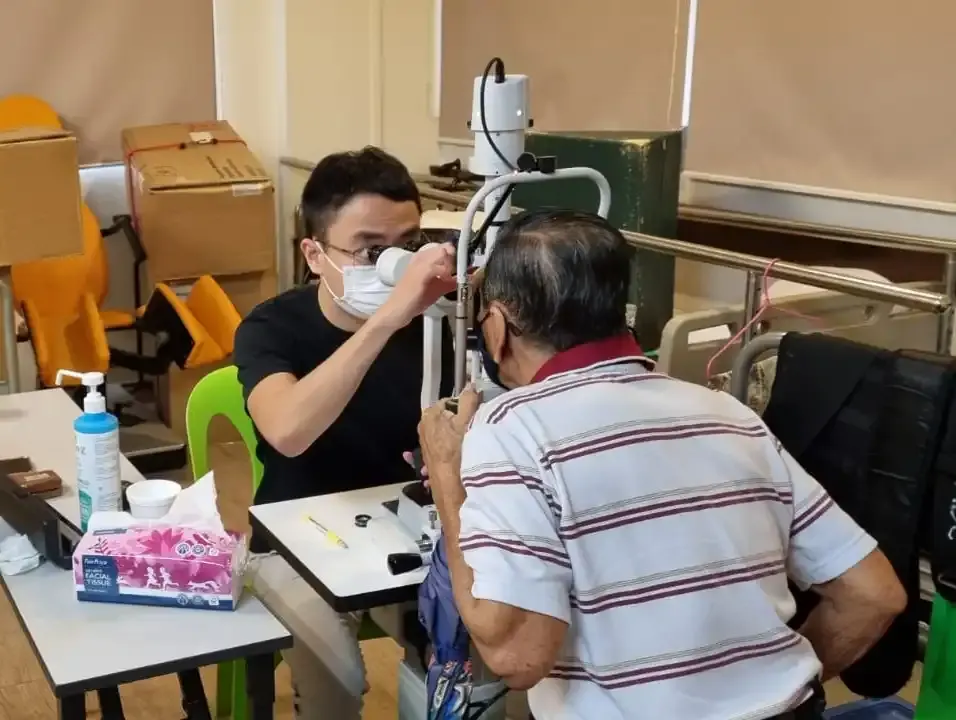 Volunteer doctor examining a senior resident's eyes at the screening event