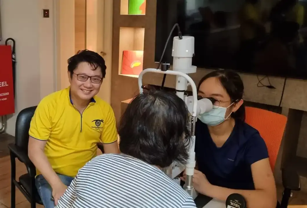Senior resident being guided through an eye test by SNEC volunteers