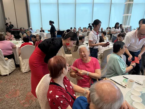 Ms Roxanne Zhang distributing ang bao to seniors